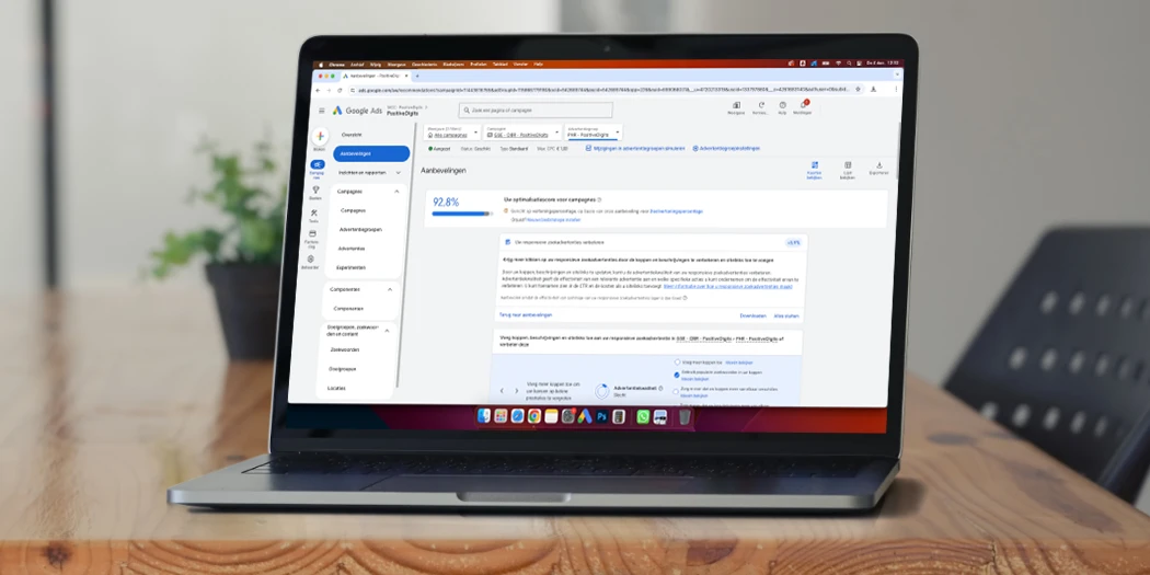 Laptop met Google Ads-dashboard voor SEA-optimalisatie op een houten tafel.