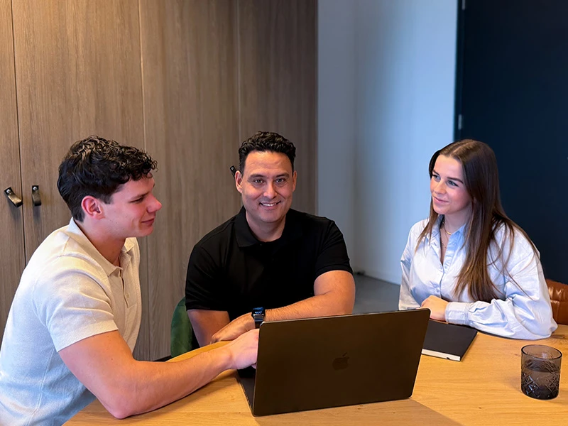 David, Max en Noor kijken samen op een laptop naar zoekmachine-adverteren.