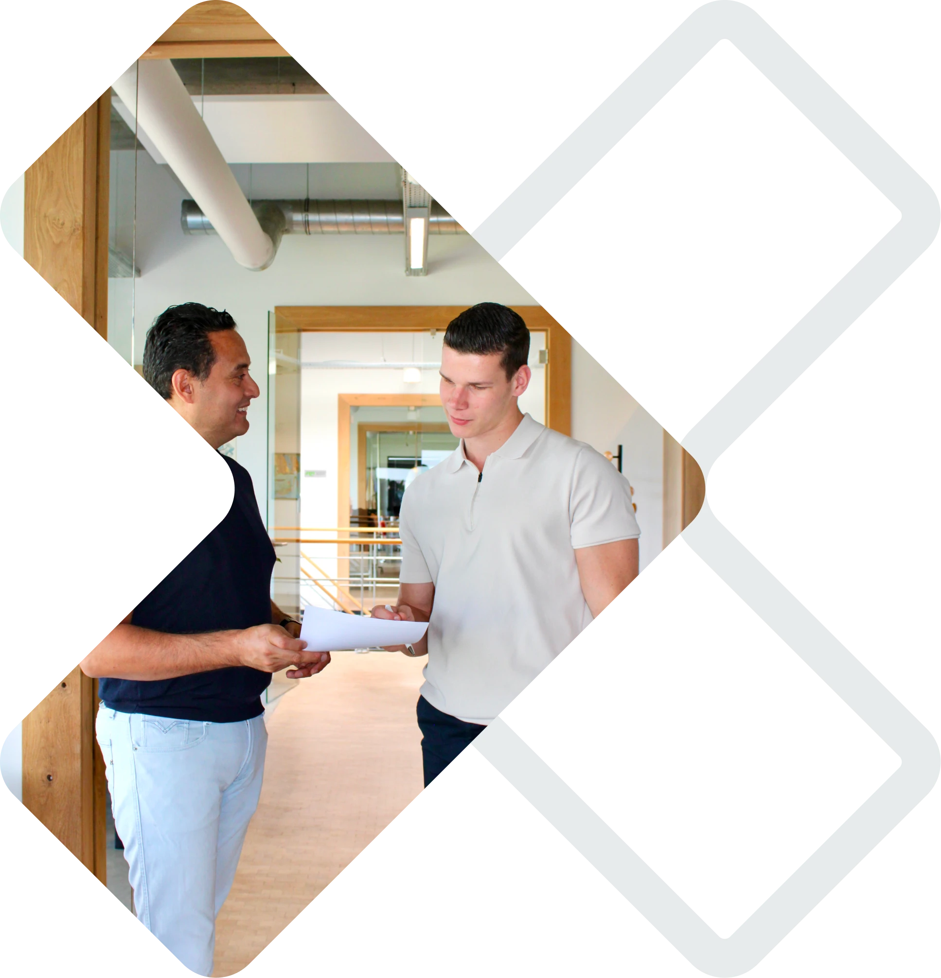 David en Max in een modern kantoor in gesprek. David toont een document aan Max.