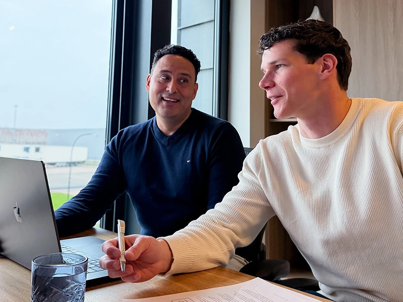 David en Max lachen samen achter de laptop, bezig met online marketing.