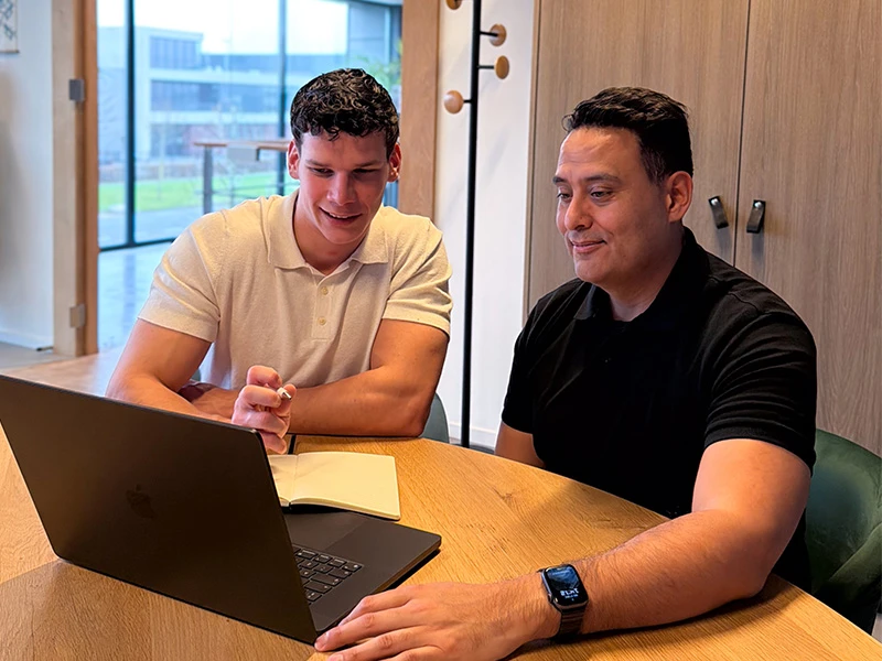 David en Max geven online marketing-advies terwijl ze samen naar de laptop kijken.