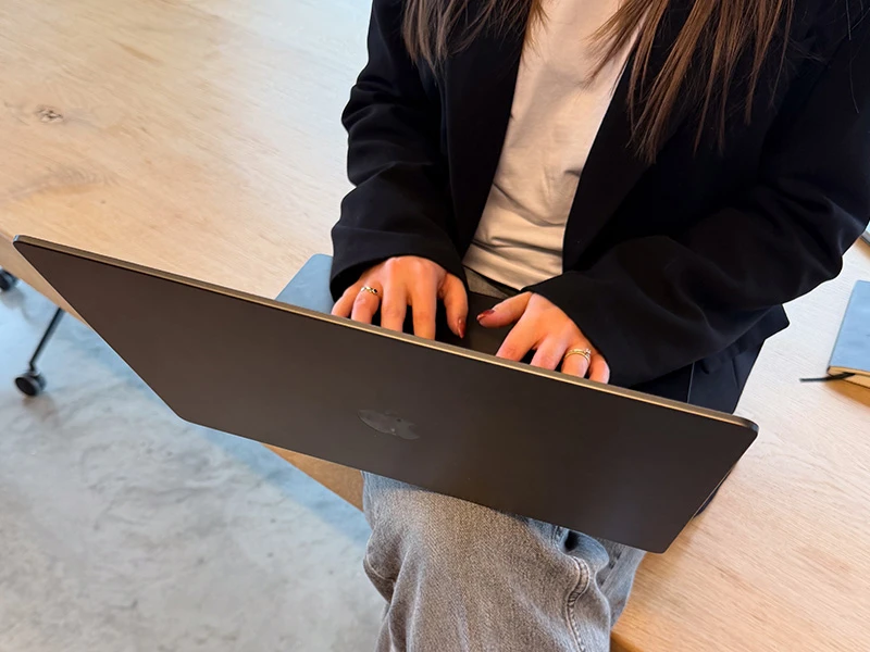 Noor werkt op een laptop aan een houten tafel, bezig met linkbuilding.