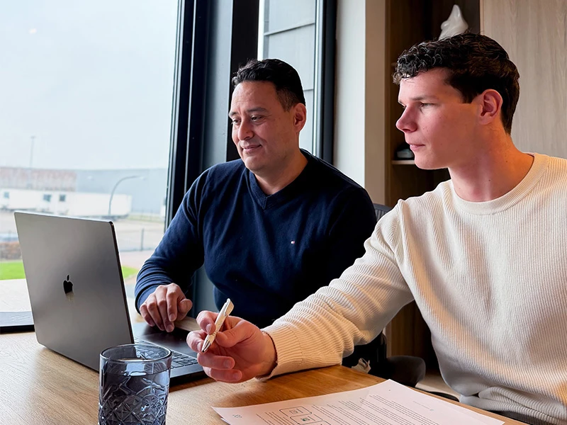 Max en David kijken samen op de laptop naar online marketing in de zorg.